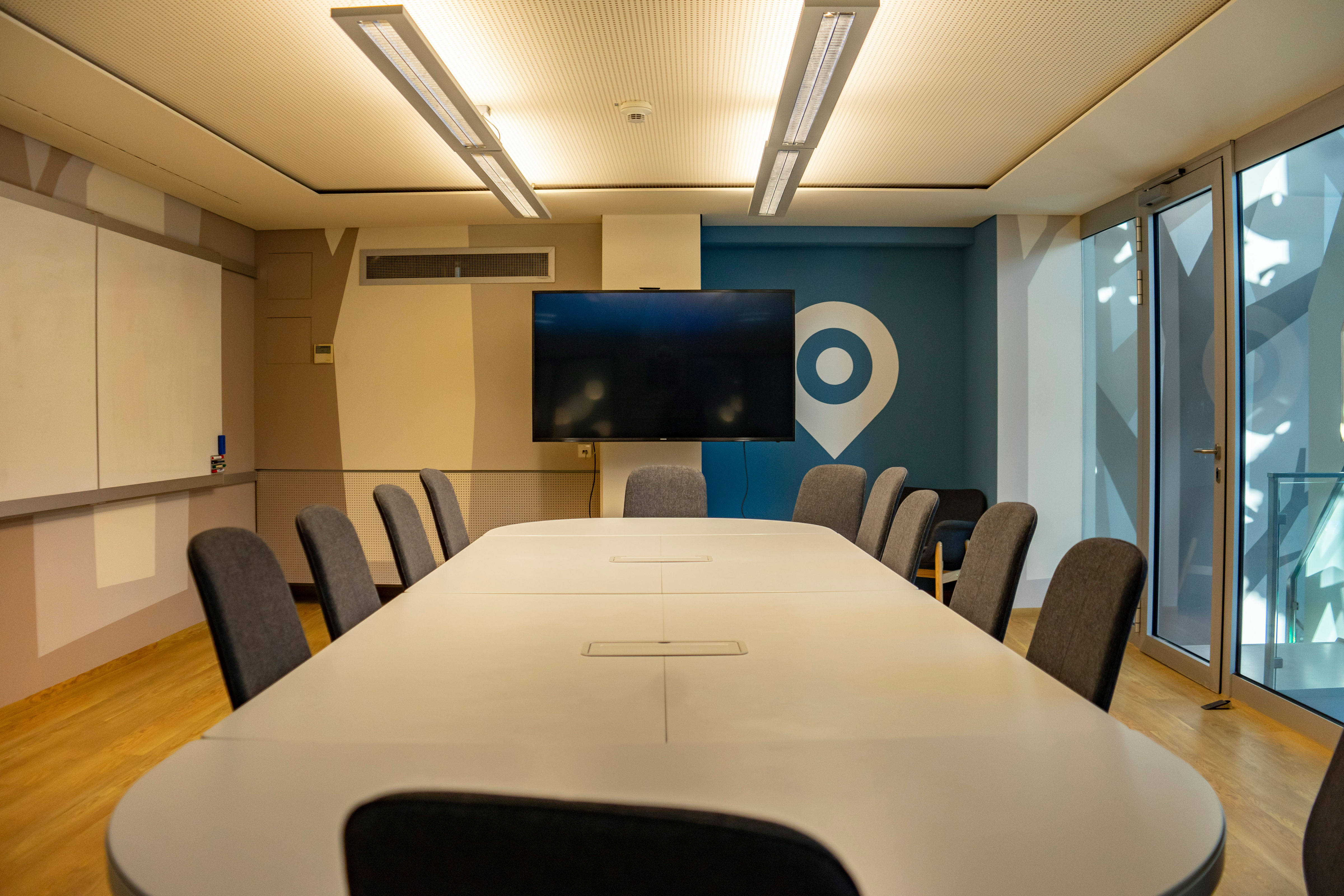 Besprechungsraum mit  großem Tisch und 12 Stühlen und großem Monitor, Whiteboard