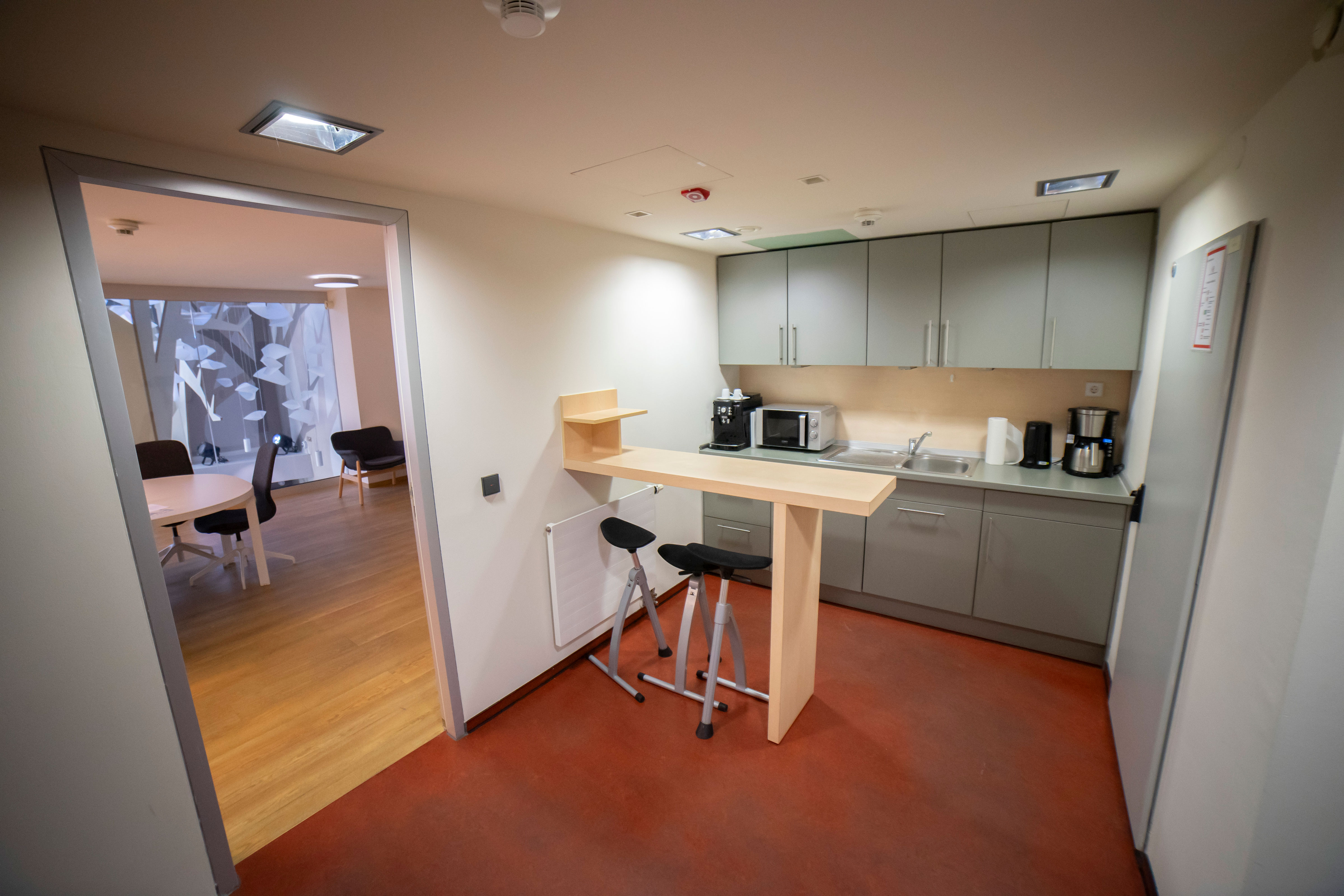 Küche mit Tresen und Stühlen, Kaffeemaschine, Mikrowelle und Kühlschrank