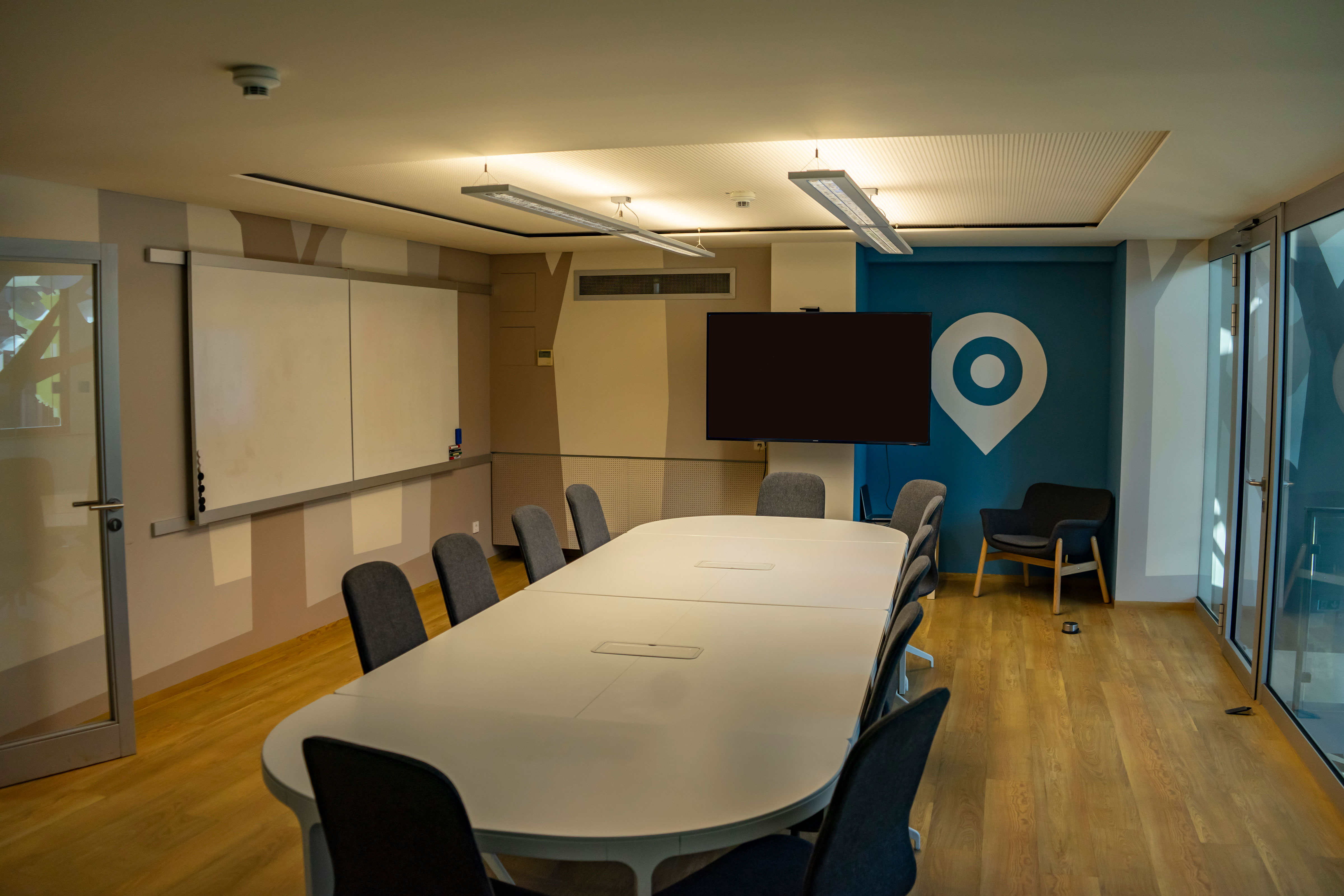 Besprechungsraum mit  großem Tisch und 12 Stühlen und großem Monitor, Whiteboard
