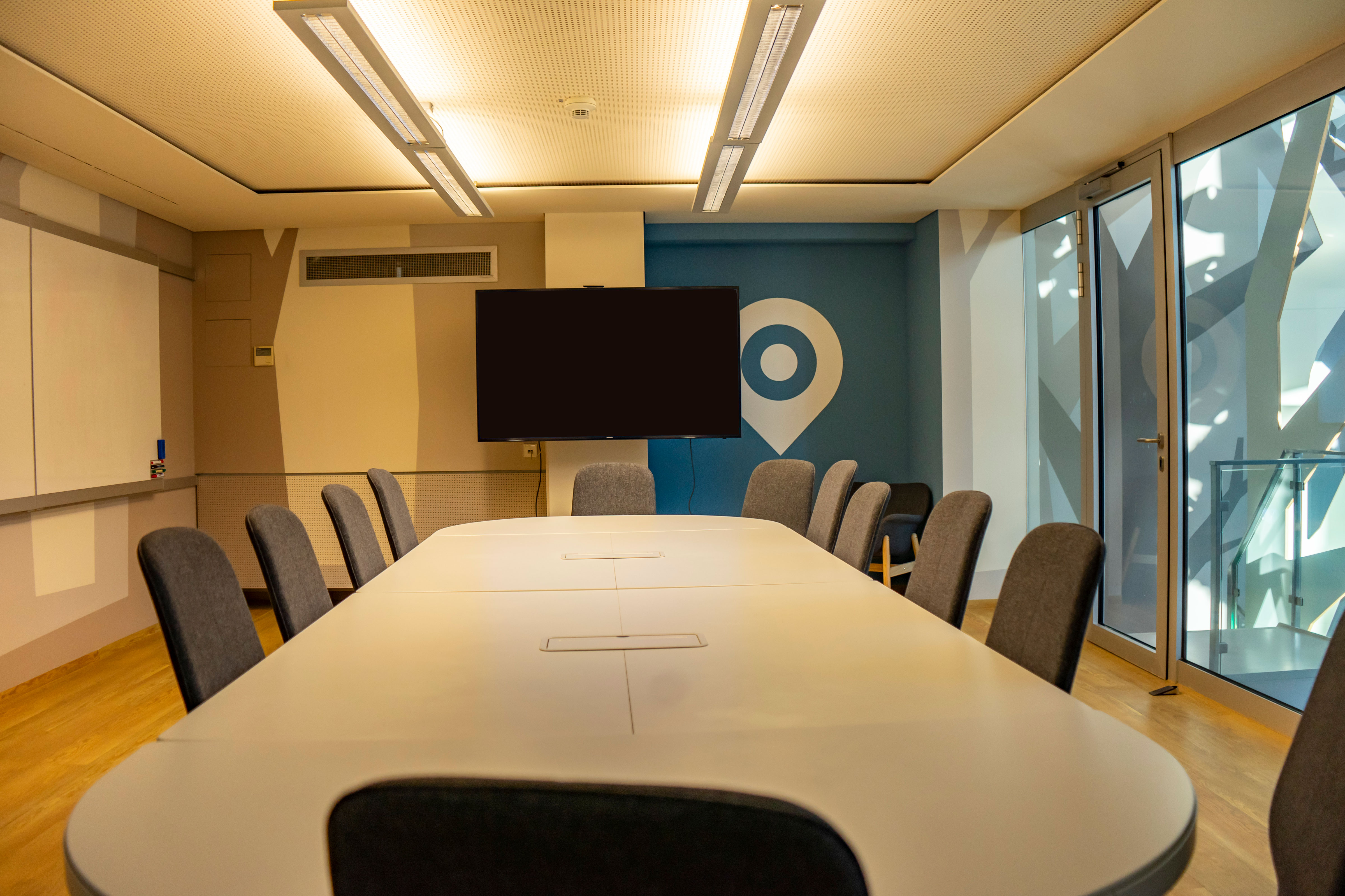Besprechungsraum mit  großem Tisch und 12 Stühlen und großem Monitor, Whiteboard