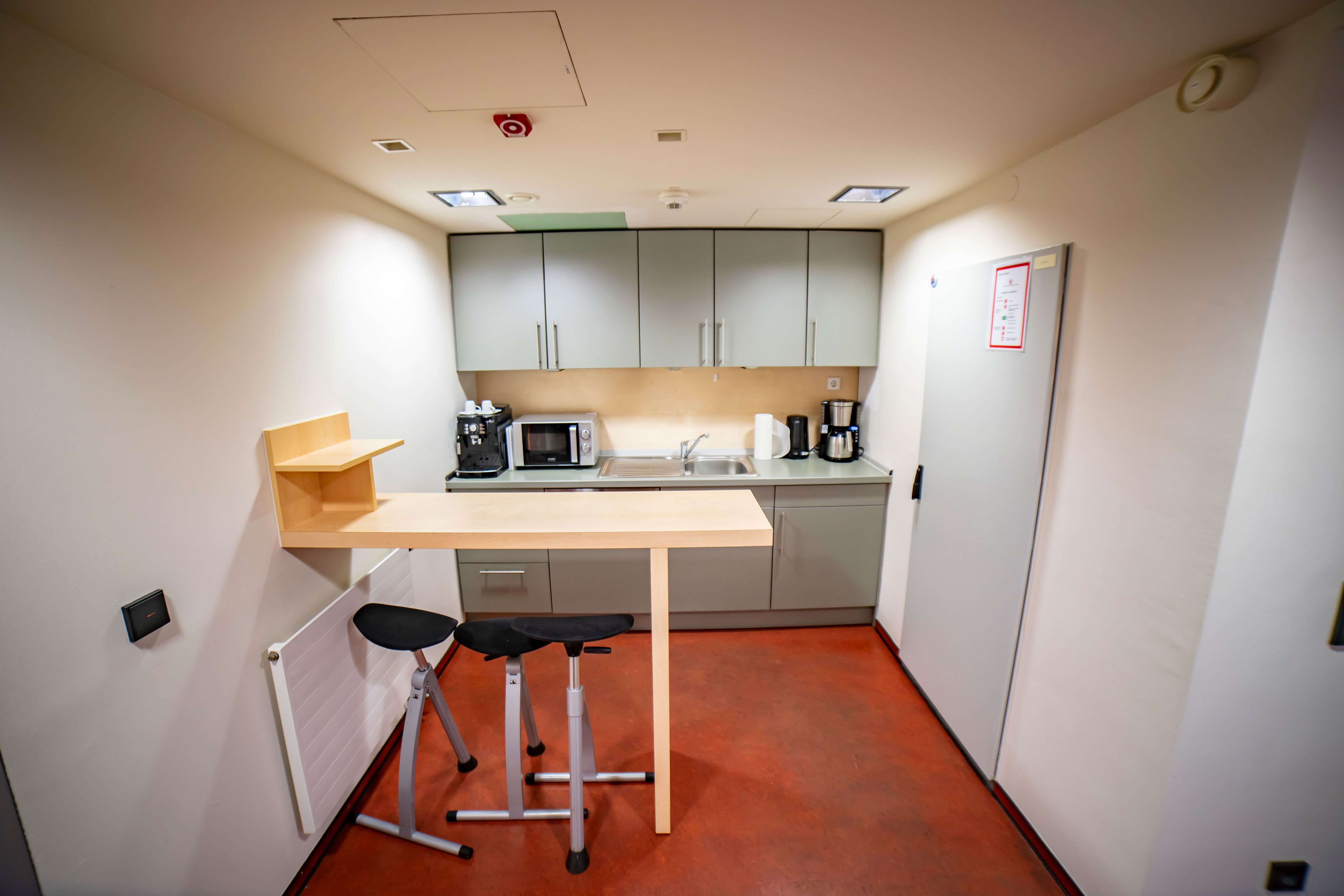 Küche mit Tresen und Stühlen, Kaffeemaschine, Mikrowelle und Kühlschrank