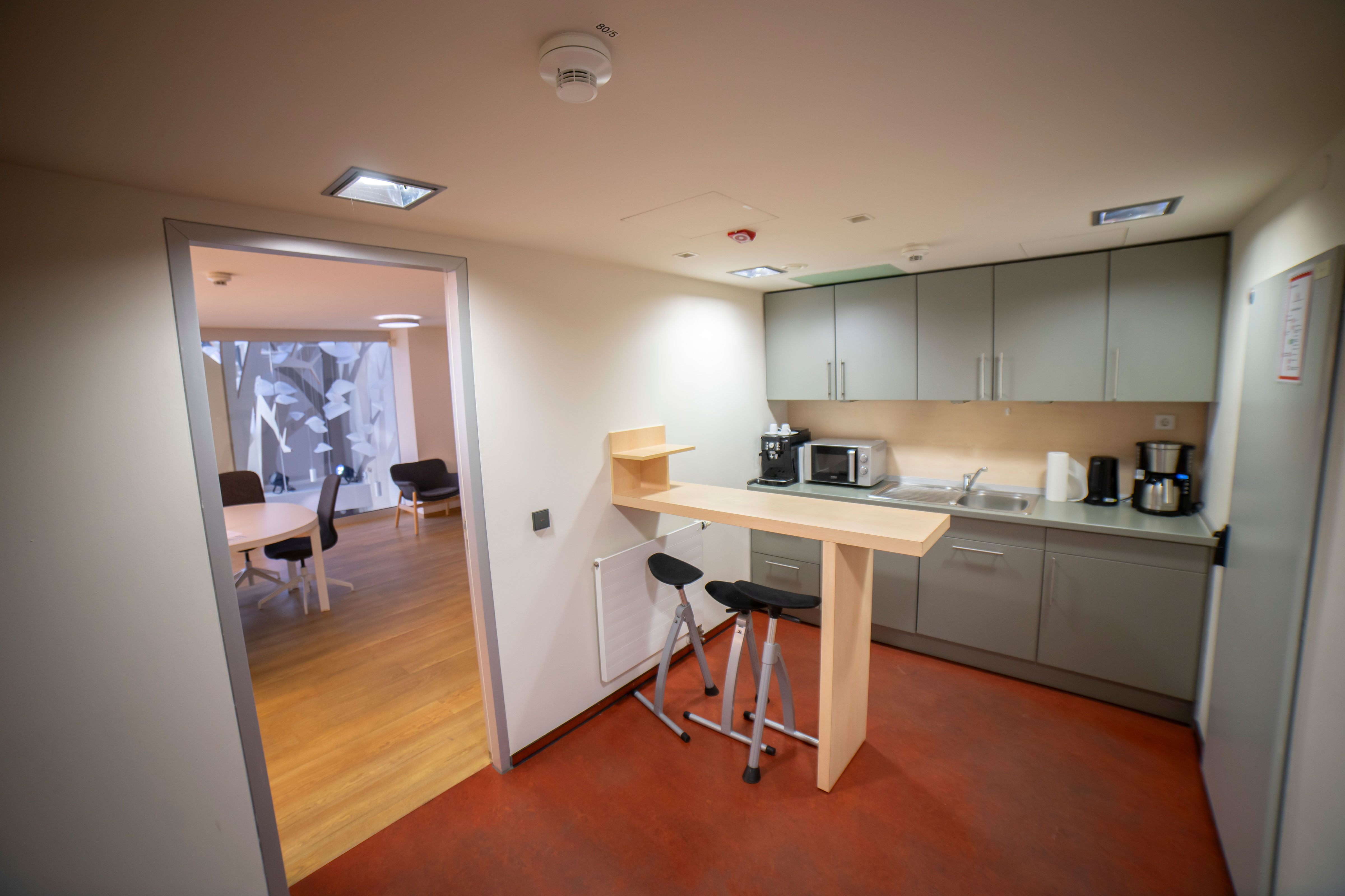 Küche mit Tresen und Stühlen, Kaffeemaschine, Mikrowelle und Kühlschrank