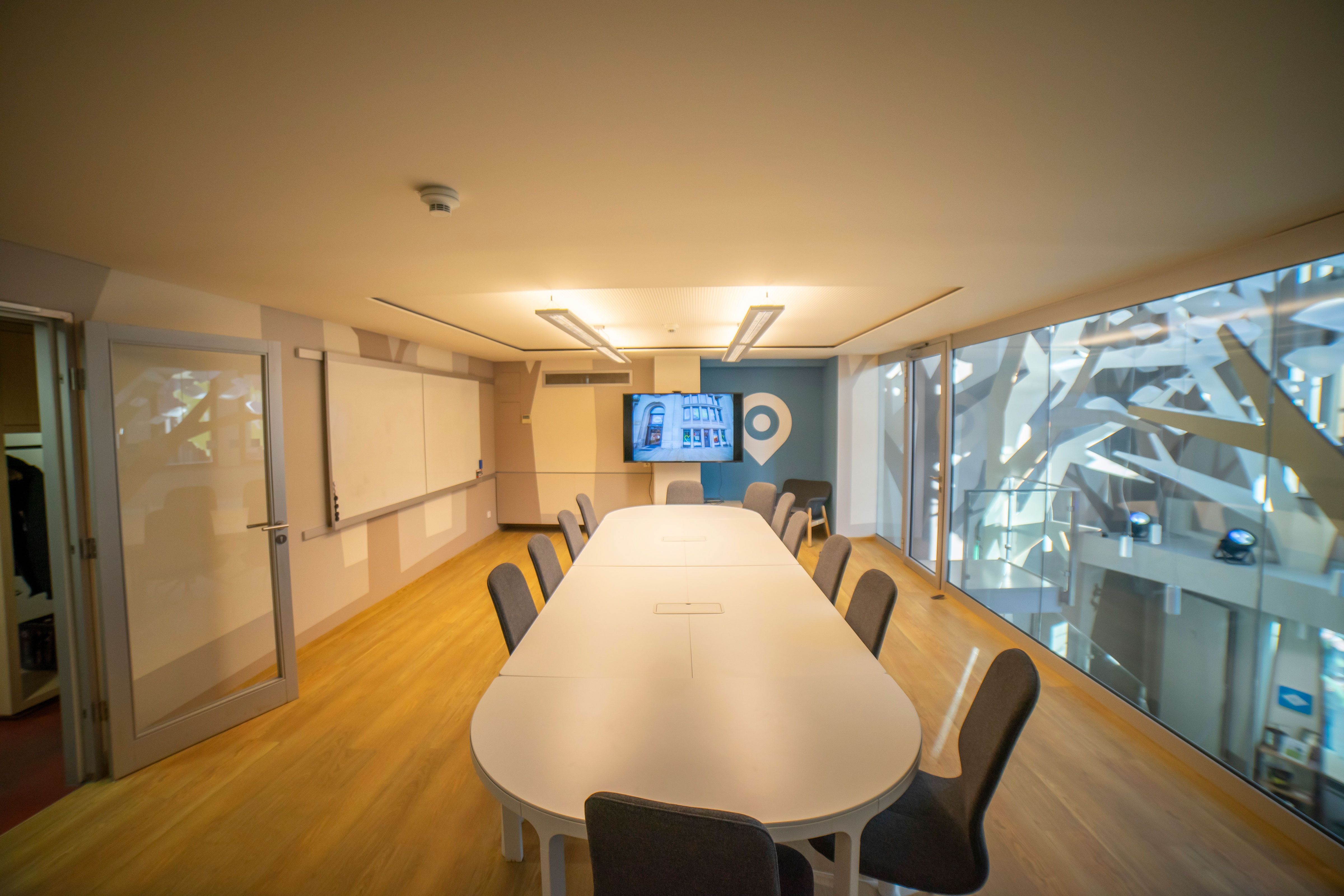Besprechungsraum mit  großem Tisch und 12 Stühlen und großem Monitor, Whiteboard