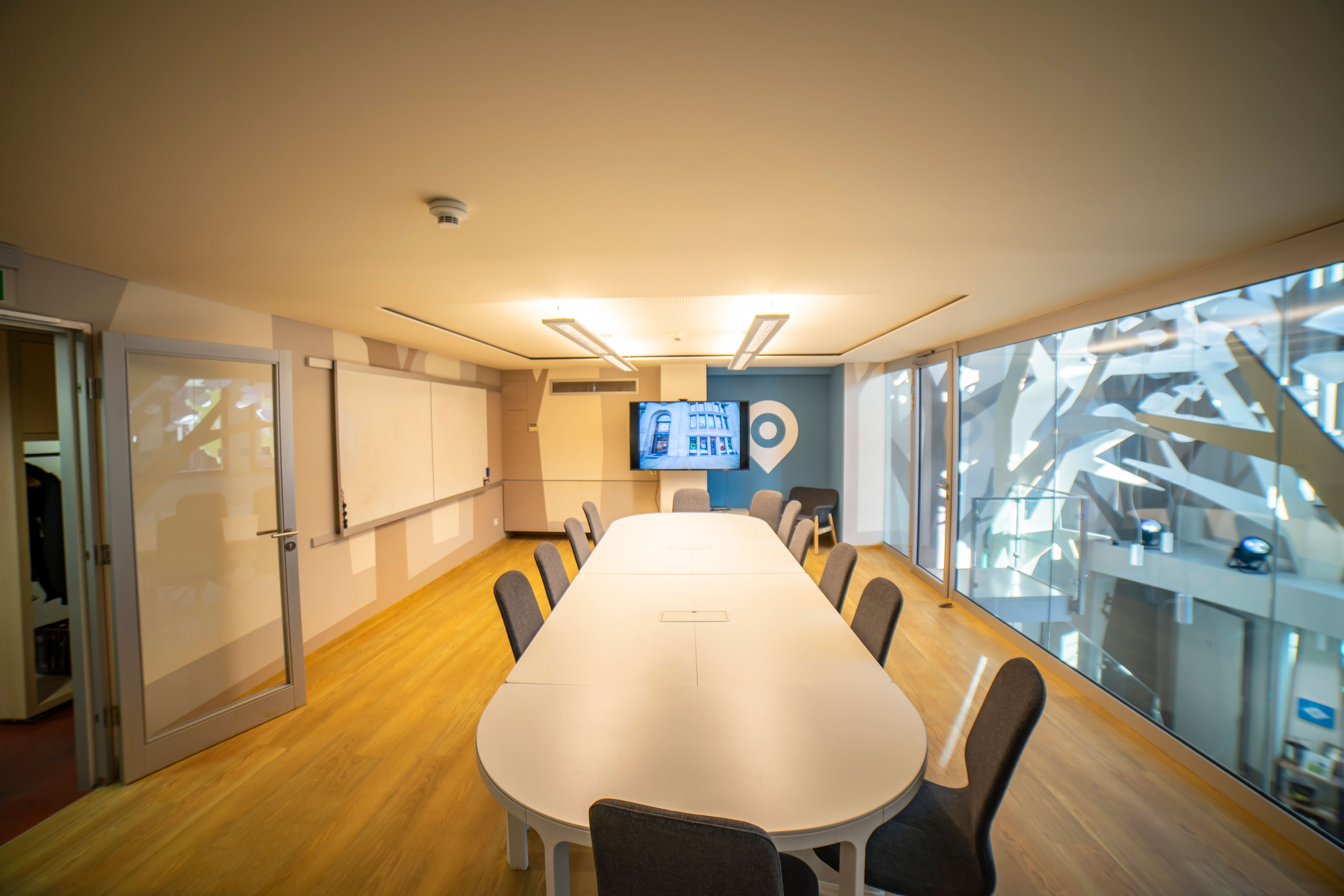 Besprechungsraum mit  großem Tisch und 12 Stühlen und großem Monitor, Whiteboard